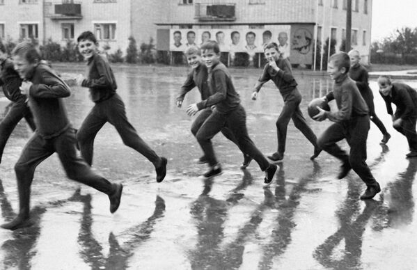 Юные белорусские спортсмены бегут по колхозной площади в надежде укрыться от дождя, 1971 год. - Sputnik Беларусь