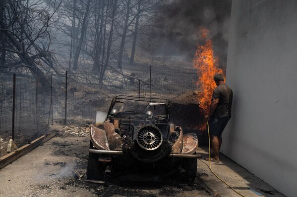Житель пытается потушить пламя во дворе дома. - Sputnik Беларусь