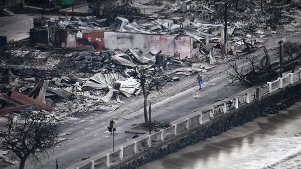 Человек идет мимо разрушенных зданий, сгоревших после лесных пожаров в западной части Мауи, Гавайи. - Sputnik Беларусь