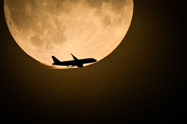 Airbus A320 кампаніі British Airways з Белфаста, які рыхтуецца да пасадкі ў Хітроў, пралятае міма поўнага месяца, які ўзыходзіць у небе над Лонданам. - Sputnik Беларусь