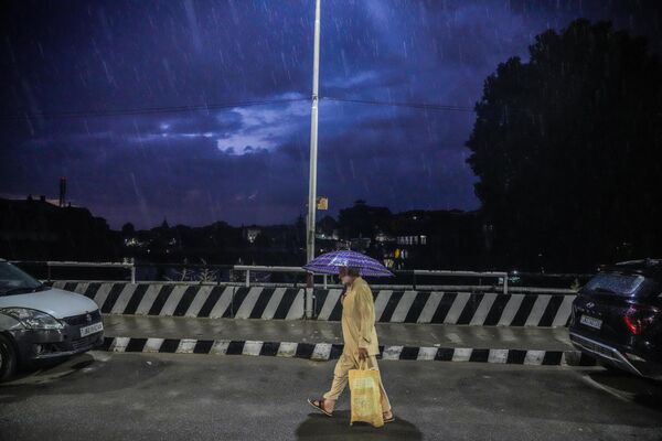 Мужчына ідзе з парасонам падчас дажджу пасля працяглай засухі ў Шрынагары, Кашмір, 18 верасня 2023 года. - Sputnik Беларусь