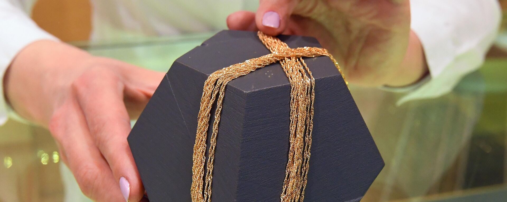 Сотрудница демонстрирует ювелирные цепочки из золота 750-й пробы производства российского завода Красцветмет 