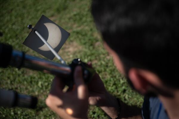 Мужчина смотрит на изображение, проецируемое телескопом, в Каракасе. - Sputnik Беларусь