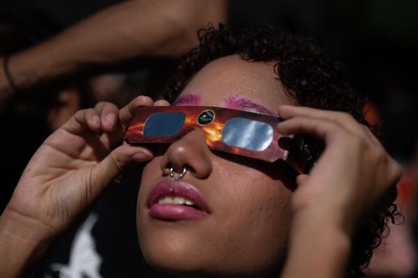 Женщина наблюдает за кольцеобразным солнечным затмением в Каракасе. - Sputnik Беларусь