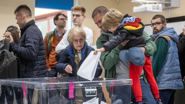 Мужчина и его ребенок голосуют на избирательном участке в Варшаве во время парламентских выборов 15 октября 2023 года. - Sputnik Беларусь