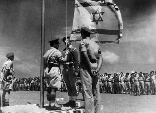 Государство Израиль было провозглашено 14 мая 1948 года Еврейским национальным советом и признано Соединенными Штатами и Советским Союзом 15 и 17 мая того же года.Соглашения, подписанные в 1949 году между Израилем и арабскими государствами, положили конец арабо-израильской войне 1948 года и установили линии перемирия между Израилем и Западным берегом, также известные как &quot;Зеленая линия&quot;, до Шестидневной войны 1967 года.На снимке, опубликованном 8 июня 1948 года, изображен израильский офицер, впервые поднимающий национальный флаг во время празднования рождения израильского государства после его провозглашения 14 мая 1948 года.   - Sputnik Беларусь