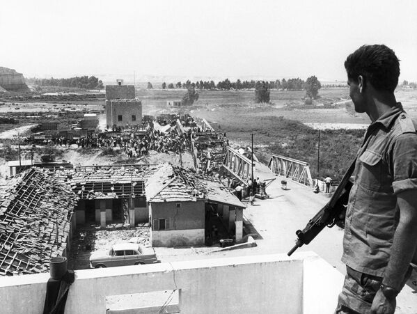 Израиль в ходе шестидневной войны с 5 по 10 июня 1967 года нанес ошеломительное поражение арабской коалиции и занял значительные территории, что в дальнейшем неоднократно приводило к конфликтам. На снимке: израильский солдат наблюдает за тем, как палестинцы по разбитому мосту пытаются сбежать в Иорданию. - Sputnik Беларусь
