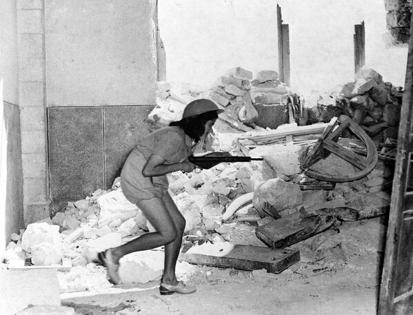 Израильская военнослужащая с пистолетом-пулеметом пробирается через развалины Сулеймановой стены в Иерусалиме 20 июля 1948 года. Она стала естественной линией фронта между палестинцами и евреями. - Sputnik Беларусь