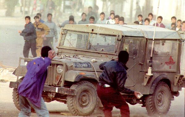 Палестинская молодежь швыряет камни в джип израильской армии во время ожесточенных столкновений, вспыхнувших 9 марта 1993 года. Причиной столкновений послужило убийство палестинца еврейским поселенцем накануне. - Sputnik Беларусь