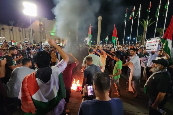 Люди сжигают флаг США во время акции протеста в столице Ливии Триполи в поддержку палестинцев поздно вечером 17 октября. - Sputnik Беларусь