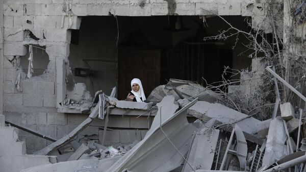 Палестинская женщина смотрит в окно после израильского удара по сектору Газа - Sputnik Беларусь