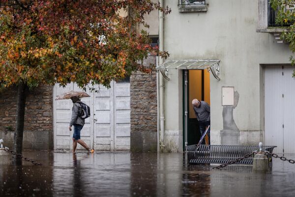 Местный житель идет по затопленной улице после сильного шторма в Кемперле, западная Франция. - Sputnik Беларусь