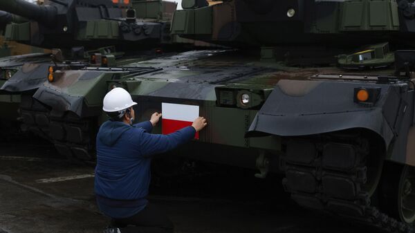 Рабочий наклеивает польский флаг на южнокорейский танк Black Panther K2 в порту ВМС Польши Гдыня - Sputnik Беларусь