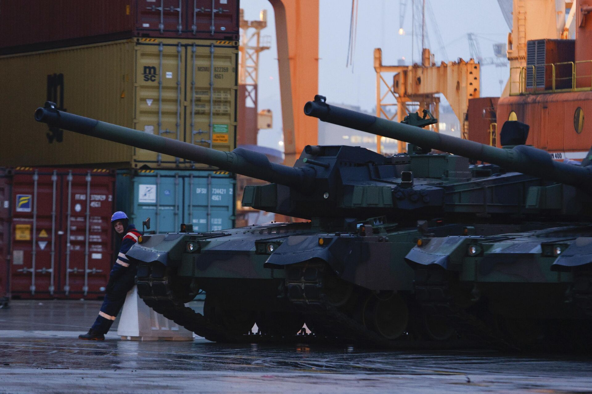 Рабочий стоит рядом с южнокорейскими танками Black Panther K2 в порту ВМС Польши в Гдыне - Sputnik Беларусь, 1920, 12.11.2023