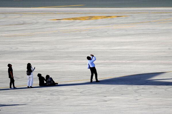 Люди наблюдают за авиашоу, укрывшись в тени самолета. - Sputnik Беларусь
