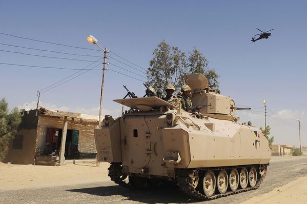 Военнослужащие египетской армии патрулируют на бронемашине при поддержке боевого вертолета во время зачистки деревень в Шейх-Зувейде, северный Синай. - Sputnik Беларусь