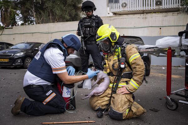 Пожарный и фельдшер доставляют кислород раненому коту, спасенному из здания, обрушенного ракетой, выпущенной из сектора Газа, в Тель-Авиве, Израиль. - Sputnik Беларусь