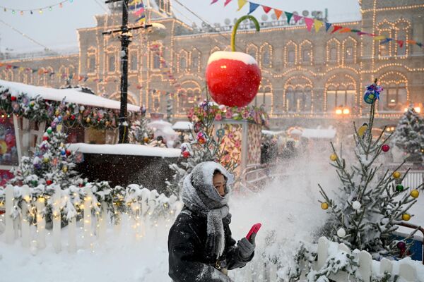 Женщина проходит мимо прилавков рождественской ярмарки на заснеженной Красной площади в Москве - Sputnik Беларусь
