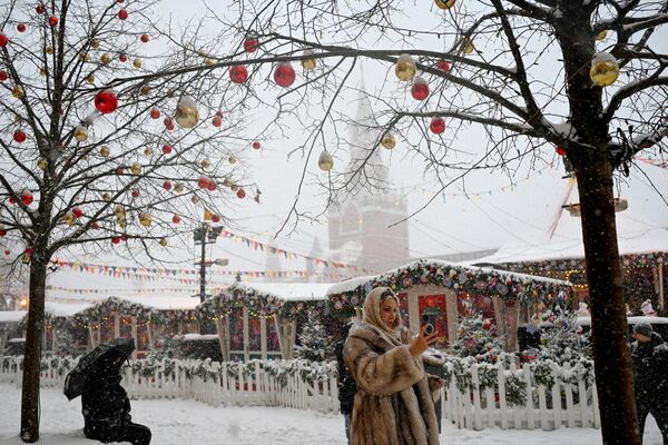 Женщина делает селфи перед прилавками рождественской ярмарки, недалеко от Спасской башни Кремля - Sputnik Беларусь