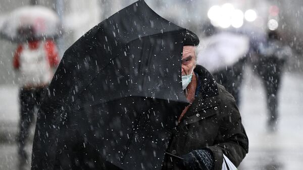 Пожилой мужчина под зонтом во время снегопада  - Sputnik Беларусь