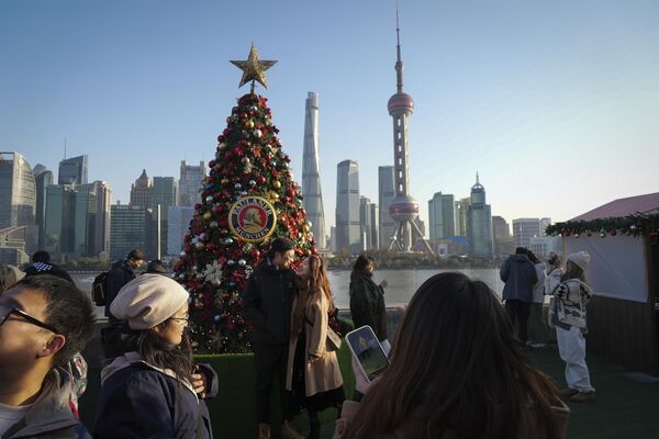 Люди фотографируются на фоне рождественское елки на Шанхайской набережной на фоне финансового района Пудун в Шанхае - Sputnik Беларусь