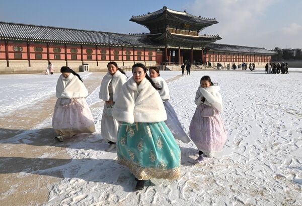 Посетительницы в традиционном платье ханбок прогуливаются по заснеженному дворцу Кенбоккун  в Сеуле. Южная Корея, 20 декабря. - Sputnik Беларусь