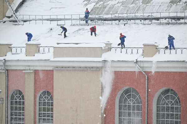 Сотрудники коммунальных служб расчищают крышу дома во время снегопада в Москве. Россия, 15 декабря. - Sputnik Беларусь