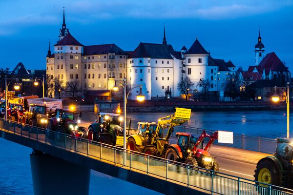 Фермеры на своих тракторах проезжают мимо замка Хартенфельс и пересекают реку Эльбу в Торгау, восточная Германия - Sputnik Беларусь