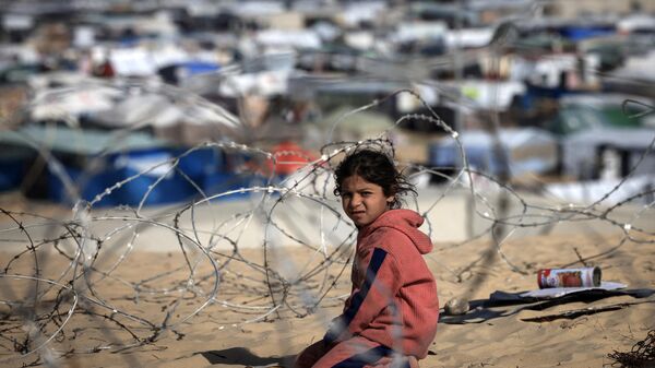 Перемещенный палестинский ребенок сидит за колючей проволокой на дюне с видом на импровизированный лагерь на границе с Египтом, к западу от Рафаха на юге сектора Газа, 14 января 2024 года - Sputnik Беларусь