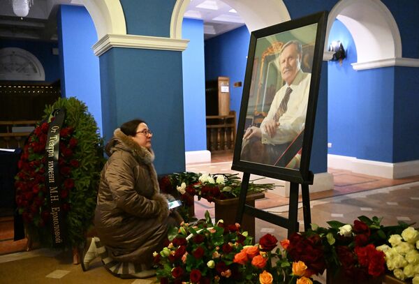 Женщина возлагает цветы к портрету Юрия Соломина в фойе Малого театра. - Sputnik Беларусь