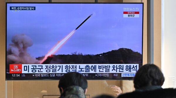 Люди смотрят на телеэкране новостную трансляцию с видеозаписью испытаний северокорейской ракеты - Sputnik Беларусь