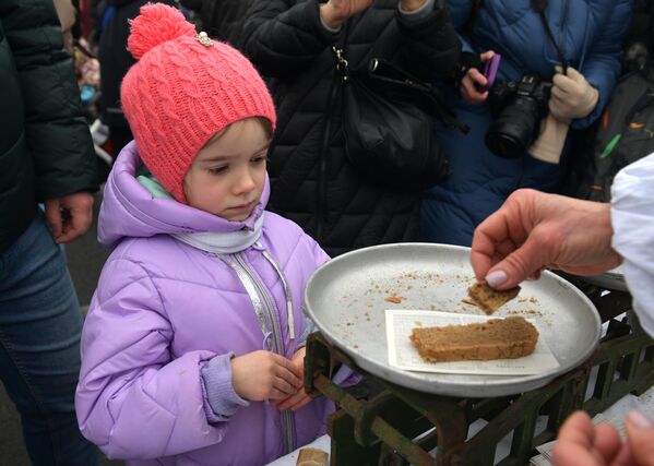 Девочка получает порцию хлеба на одной из площадок в рамках мероприятий, посвященных 80-й годовщине полного снятия блокады Ленинграда, на Дворцовой площади в Санкт-Петербурге. - Sputnik Беларусь
