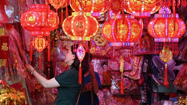 Женщина выбирает китайские украшения в магазине в Джакарте - Sputnik Беларусь