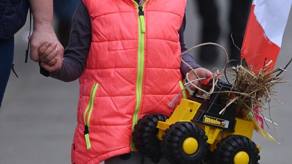 Ребенок с игрушечным трактором на акции протеста против климатических мер ЕС и украинского импорта в Варшаве - Sputnik Беларусь