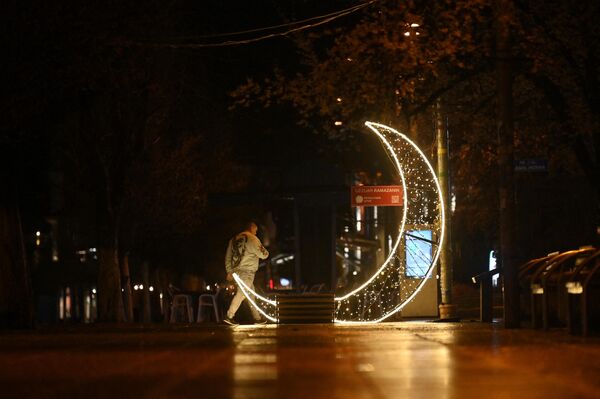 Мужчина идет перед украшением в форме полумесяца в центре Приштины, Республика Косово. - Sputnik Беларусь