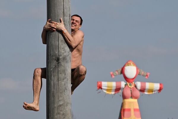 Мужчина лезет по столбу на праздновании Масленицы в этнографическом парке-музее Этномир в Подмосковье - Sputnik Беларусь