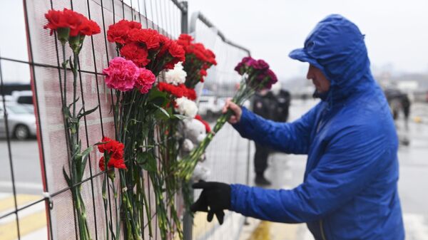 Люди несут цветы к зданию концертного зала Крокус Сити Холл - Sputnik Беларусь