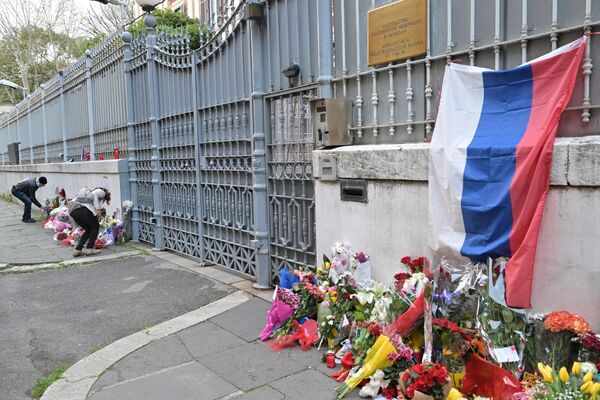 Люди возлагают цветы к импровизированному мемориалу жертвам возле посольства России в Риме - Sputnik Беларусь