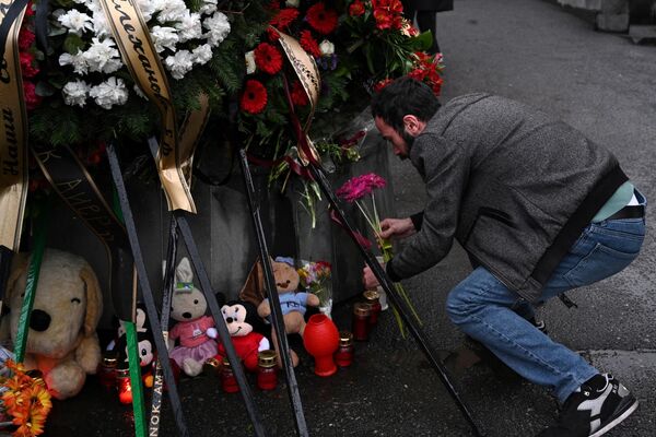 Мужчина возлагает цветы к импровизированному мемориалу перед посольством России в Ереване - Sputnik Беларусь