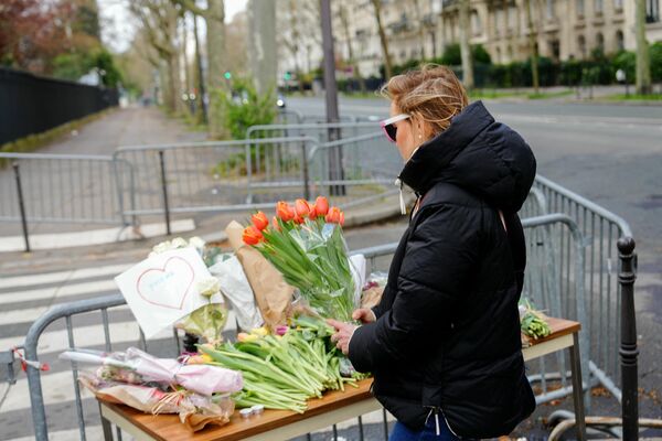 Женщина держит букет цветов у импровизированного мемориала перед посольством России в Париже - Sputnik Беларусь