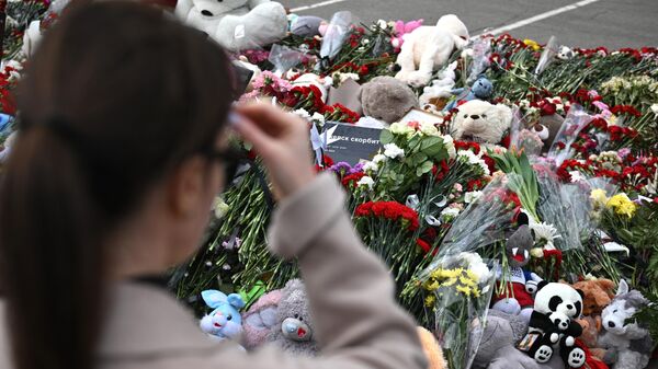Женщина у стихийного мемориала возле подмосковного Крокус Сити Холла  - Sputnik Беларусь