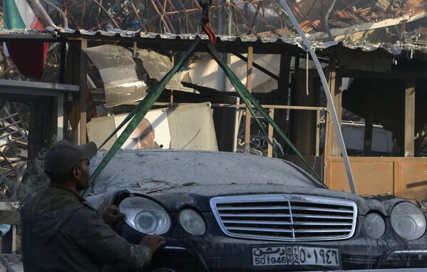 Сотрудники службы экстренной помощи и безопасности осматривают повреждения на месте ударов по зданию рядом с иранским посольством в столице Сирии Дамаске. - Sputnik Беларусь