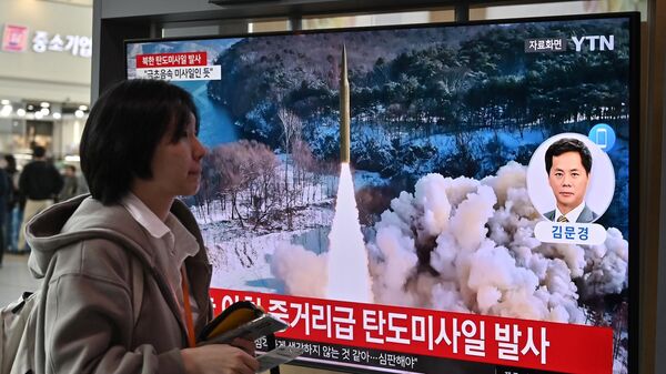 Женщина проходит мимо телеэкрана, на котором транслируется новостная передача с видеозаписью испытаний северокорейской ракеты - Sputnik Беларусь