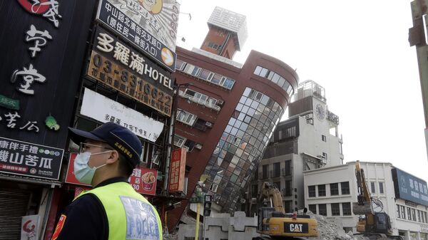 Офицер полиции стоит на страже возле частично обрушившегося здания через день после мощного землетрясения в городе Хуалянь, восточный Тайвань, Китай - Sputnik Беларусь