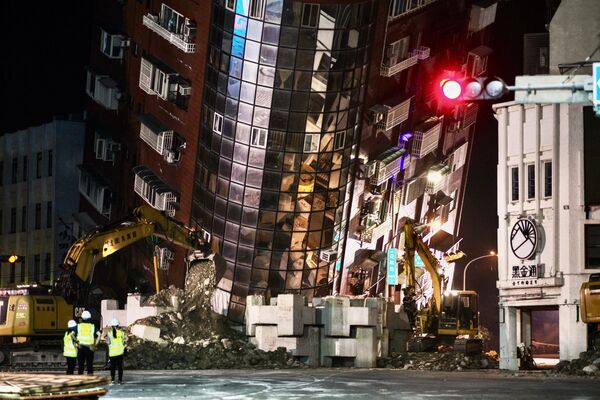 Сотрудники службы экстренной помощи перед частично разрушенным зданием, склонившимся над улицей в Хуаляне. - Sputnik Беларусь