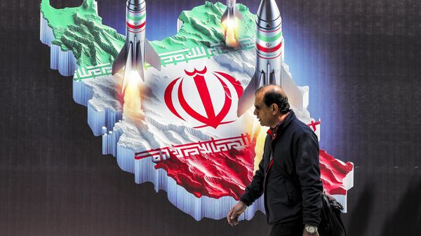 Мужчина проходит мимо баннера с изображением запуска ракет с изображения карты Ирана - Sputnik Беларусь