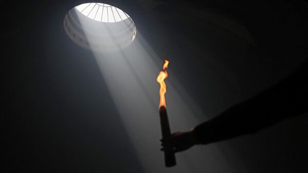 Православный христианин держит зажженную свечу в храме Гроба Господня в Иерусалиме во время ежегодной церемонии Благодатного огня, за день до православной Пасхи, 4 мая 2024 года - Sputnik Беларусь