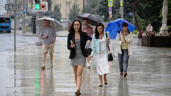 Люди идут по улице во время дождя - Sputnik Беларусь