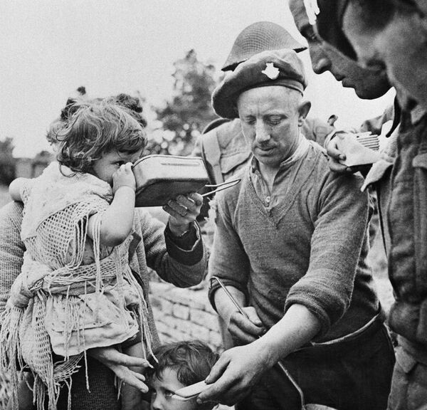 Французские беженцы, включая женщин и детей, собираются вокруг британских солдат, которые раздают горячую еду в Центре питания гражданских лиц на плацдарме, 16 июня 1944 года. Многие из беженцев не ели в течение трех и более дней.  - Sputnik Беларусь