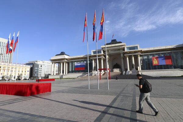 Мужчина проходит мимо площади Сухэ-Батора, украшенной государственными флагами Монголии и России. - Sputnik Беларусь